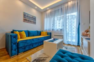 uma sala de estar com um sofá azul e almofadas amarelas em Hugo Apartmani Zlatibor em Palisat