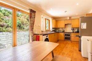 a kitchen with a wooden table and a large window at Langridge Highland Home in Badcaul