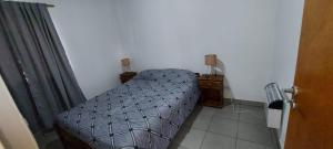 Un dormitorio pequeño con una cama y dos mesitas de noche. en DEPARTAMENTO ORTEGA Junin, en Junín