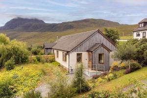 a cottage in a garden with mountains in the background at Langridge Highland Home in Badcaul