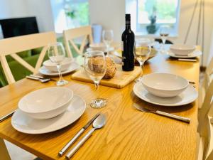 a wooden table with white plates and glasses of wine at The Ilkley Hideaway in Ilkley