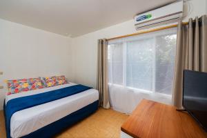 a bedroom with a bed and a tv and a window at Hostal North Seymour in Puerto Ayora