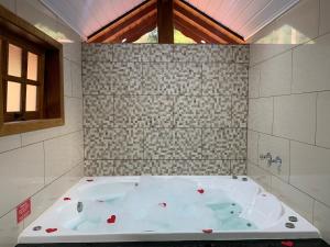 a large bath tub in a bathroom with a window at Chales Bela Serra in Monte Verde