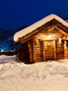 une cabane en rondins recouverte de neige la nuit dans l'établissement Relais du Chateau Blanc, à La Thuile