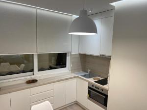 uma cozinha com armários brancos e uma luz pendente em TIRANA CITY CENTER STUDIO em Tirana