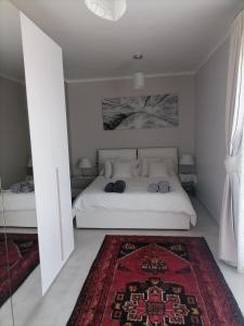 a bedroom with a white bed and a red rug at SoleLuna Apartment 2 in Santa Elisabetta