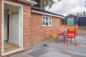 a patio with colorful chairs and a table at Luxurious rural retreat - Holt Coach House in Sudbury