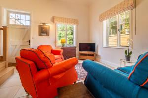 a living room with two orange chairs and a television at Luxurious rural retreat - Holt Coach House in Sudbury