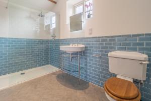 a blue tiled bathroom with a toilet and a sink at Luxurious rural retreat - Holt Coach House in Sudbury