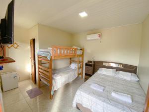 a bedroom with two bunk beds and a television at Pousada Brisa do Mar in Barrinha