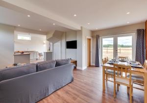 a living room with a couch and a table and a kitchen at The Cartlodge in Woolpit