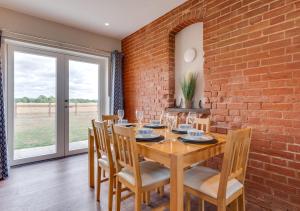 a dining room with a brick wall and a wooden table and chairs at The Cartlodge in Woolpit