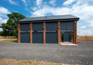 a black building with a garage with a fence at The Cartlodge in Woolpit