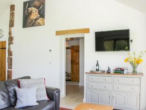 een woonkamer met een bank en een tv aan de muur bij Vitula Cottage in Shrewsbury