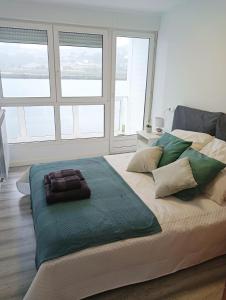 Cama grande en habitación blanca con ventanas en Apartamento Ría Navia, en Navia