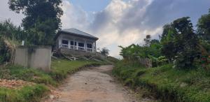 ein Haus auf einem Hügel neben einer unbefestigten Straße in der Unterkunft Saka Laka in Fort Portal