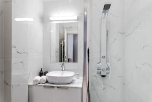 a white bathroom with a sink and a shower at BEAUTIFUL ΝΕW CENTRAL APPARTMENT in Athens