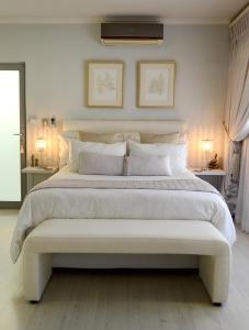 a large white bed with a bench in a bedroom at Augusta Palms - White Room in Centurion