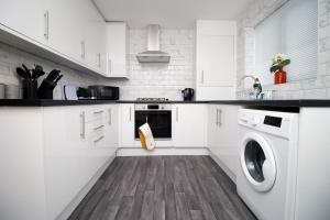 una cucina con mobili bianchi, lavatrice e asciugatrice di 2 Bedroom House on Holmes Hill Road- Free Parking, Wi-Fi & Patio a Bristol