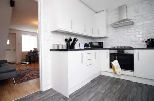 a kitchen with white cabinets and a living room at Newly Renovated Home With Free Parking in Bristol