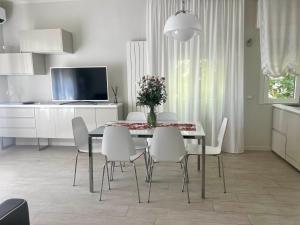 comedor con mesa y sillas blancas en Stunning Apartment 300mt from the beach en Forte dei Marmi