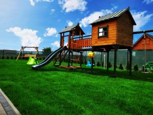 a playground with a tree house and a slide at Domki Tabaluga in Rusinowo
