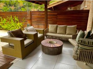 eine Terrasse mit Stühlen, einem Tisch und einem Zaun in der Unterkunft Casa Pé na Areia in Pauba
