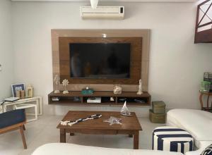 a living room with a television and a coffee table at Casa Pé na Areia in Pauba