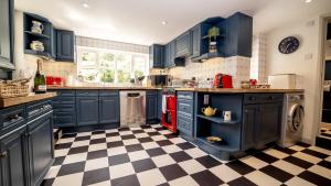 a kitchen with blue cabinets and a checkered floor at The Sherborne Cottage in Sherborne