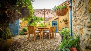 uma mesa e cadeiras com um guarda-sol num pátio em The Sherborne Cottage em Sherborne