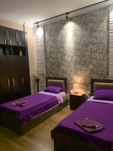 Dos camas en una habitación con sábanas moradas. en Downtown-home in the heart of old Tbilisi, en Tiflis