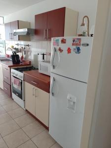 a kitchen with white appliances and a white refrigerator at A minutos del centro Con cochera in Trujillo