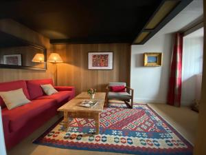 uma sala de estar com um sofá vermelho e uma mesa em Le Chalet des Pyrénées em Arcizans-Avant