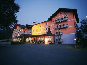 Un grand bâtiment est éclairé la nuit. dans l'établissement Hotel Pachernighof, à Velden am Wörther See