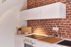 a kitchen with white cabinets and a brick wall at AQVAE Unconventional Country House 