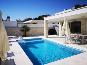 a swimming pool with an umbrella and a house at La Villa du Soleil in Sukošan