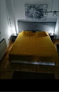 a bed with a yellow comforter in a room at W Apartman in Gornji Milanovac