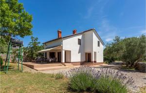 a small white house in a garden with trees at Stunning Home In Muraj With Kitchen in Kornić