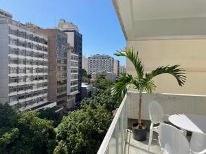 a balcony with white chairs and a palm tree at Precioso apartamento con terraza y piscina in Rio de Janeiro