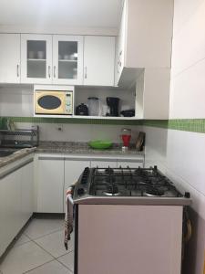 uma cozinha com armários brancos e um forno com placa de fogão em TRIPLEX PRAIA DO PERÓ em Cabo Frio