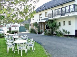 a woman sitting at a table in front of a building at Hotel Restaurant Schmidter Bauernstube in Nideggen