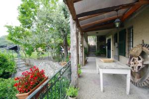 une terrasse couverte d'une maison avec une table et des fleurs dans l'établissement Il Mulino del Castello, à Garlenda