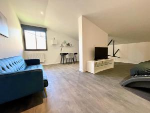 een woonkamer met een blauwe bank en een televisie bij Residence Belfort in Le Mans