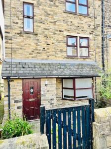 a brick house with a red door and a wooden gate at Ilkley Place in Ilkley