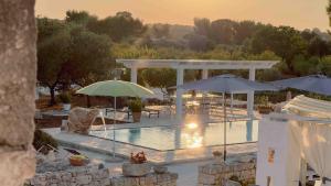 einen Pool mit Sonnenschirmen und Stühlen sowie einen Pavillon in der Unterkunft Masseria Piatone in Ostuni