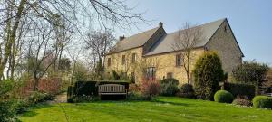 a large brick house with a bench in the yard at Au Jardin Des Violettes in Mahéru