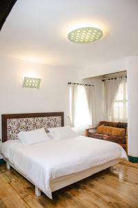 a bedroom with a large white bed and a couch at El Despertar Hotel in Jericó