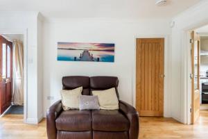 una sala de estar con un sofá de cuero marrón en una habitación en River view cottage, in Cockermouth center en Cockermouth