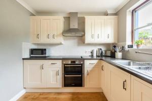 a kitchen with white cabinets and a sink at River view cottage, in Cockermouth center in Cockermouth