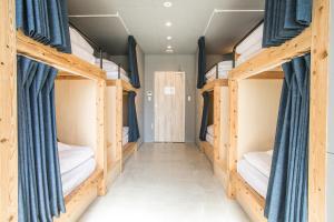福岡的住宿－Hostel STAND BY ME，一间设有四张双层床和蓝色窗帘的房间